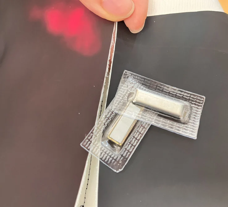 A magnetic fastener attached to the garment, beside a visible heat-sensitive color change.