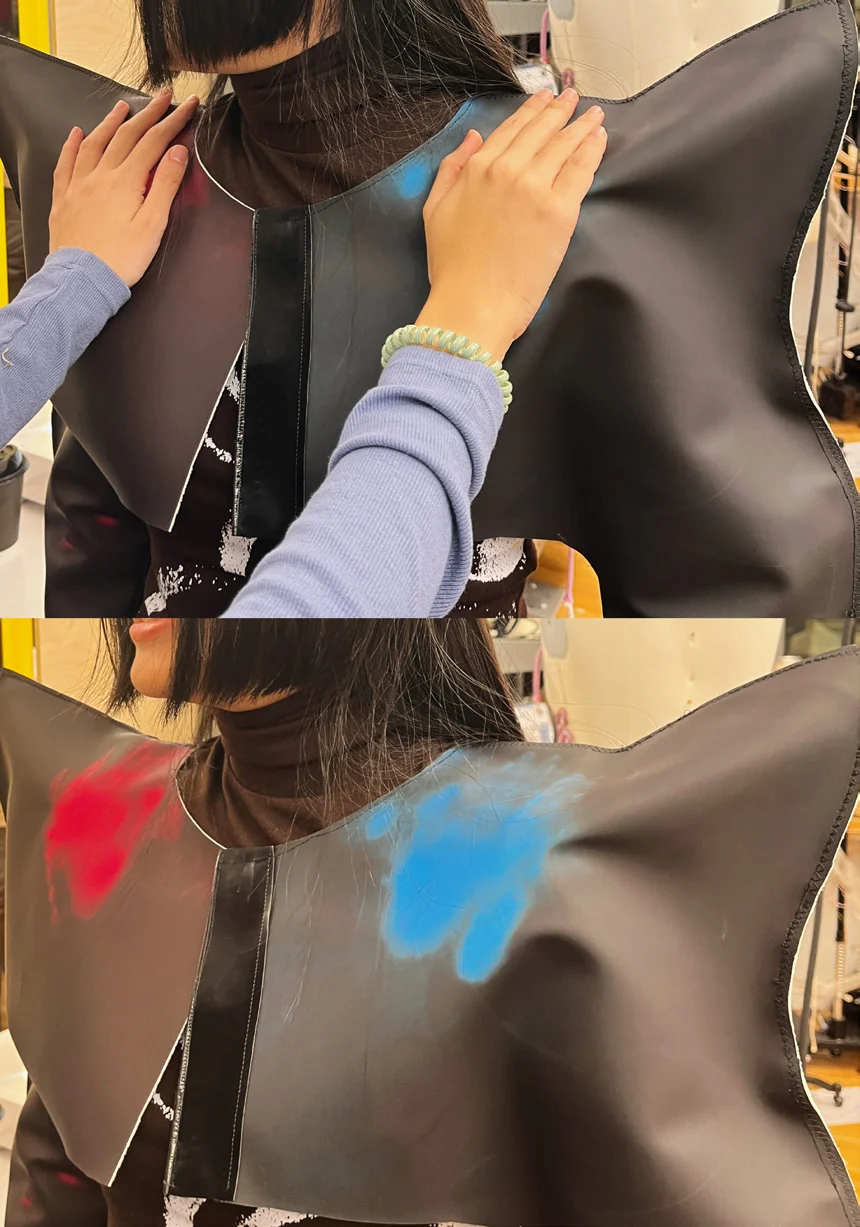 A friend touches the worn garment, leaving visible colored traces on the fabric.
