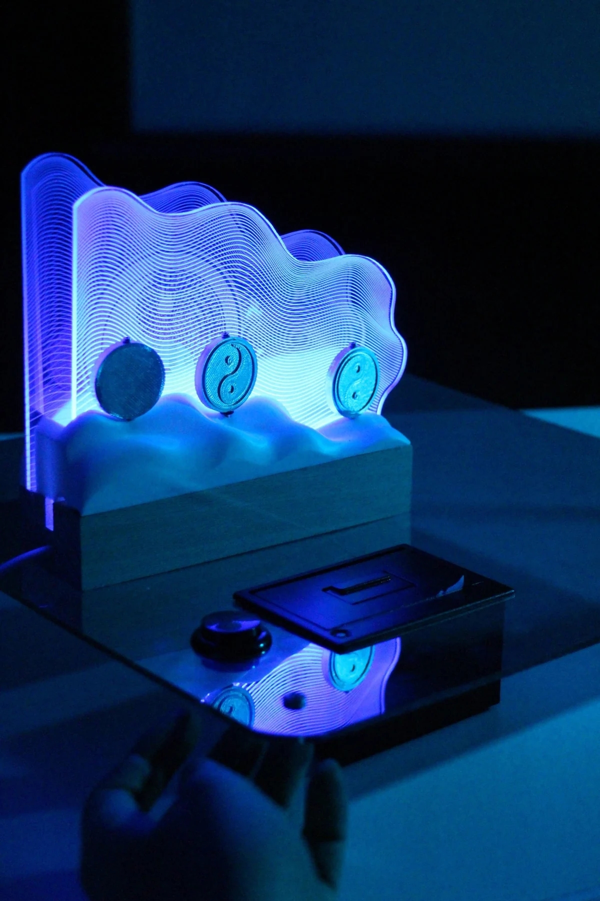 The finished installation glows blue above its base in a dark exhibition setting.
